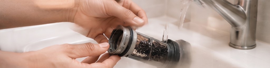Nettoyage du filtre de vidange d'un lave-linge sous l'eau